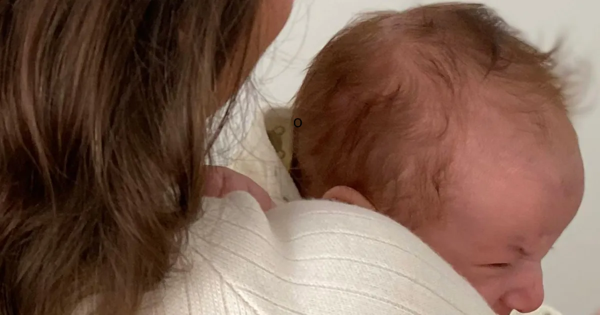Neonato appoggiato alla spalla di un adulto in un momento di contatto fisico e vicinanza.