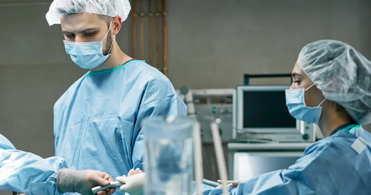 Équipe medica in sala operatoria con camici sterili e mascherine durante una procedura critica.