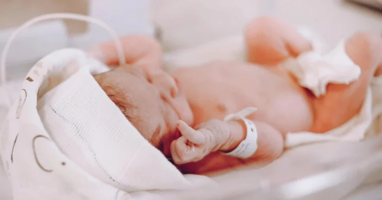 Neonato prematuro protetto in incubatrice all'interno di un reparto di terapia intensiva neonatale.